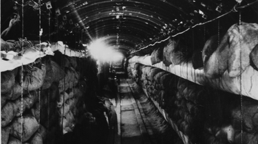 Im Hochkantformat wurde in den langen Tunnel mit der gewölbten Decke hinein fotografiert. Auf beiden Seiten sind Regale voller Leinensäcke.